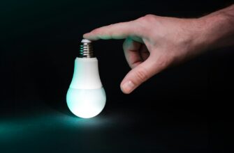 Рука трогает лампочку и она горит