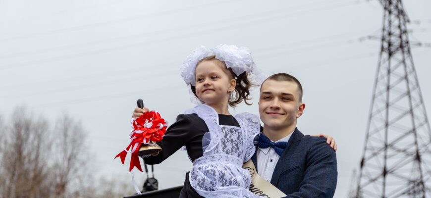 Выпускник держит первоклассницу на руках
